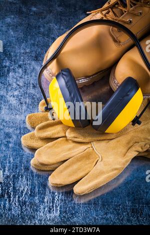 Bottes de travail en cuir, gants de protection et écouteurs pour la réduction du bruit sur les surfaces métalliques rayées Design concept Banque D'Images