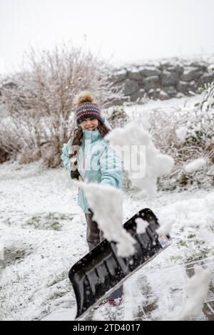 Fille, 9 ans, avec pelle à neige à l'extérieur Banque D'Images