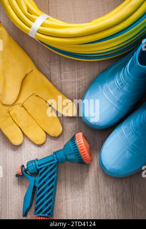 Tuyau en caoutchouc de pulvérisation à la main avec buse de pulvérisation gants de sécurité en cuir et bottes en caoutchouc sur planche de bois Agriculture concept Banque D'Images