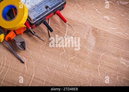 Outils électriques pince testeur de résistance d'isolement tournevis rouleau de ruban isolant jaune organisé espace copie sur planche de bois Banque D'Images