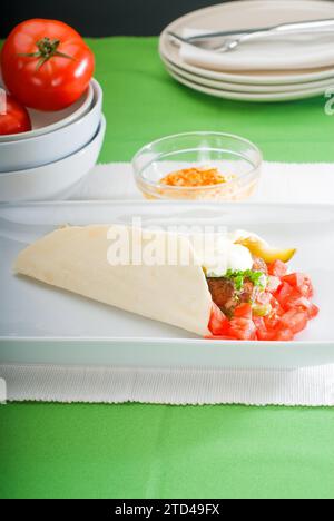 Enveloppement traditionnel frais de falafel sur pain pita avec des tomates fraîches hachées, Photographie alimentaire Banque D'Images