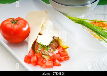 Enveloppement traditionnel frais de falafel sur pain pita avec des tomates fraîches hachées, photographie alimentaire Banque D'Images