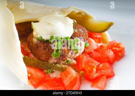 Enveloppement traditionnel frais de falafel sur pain pita avec des tomates fraîches hachées, photographie alimentaire Banque D'Images