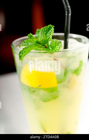 Cocktail de mojito caipirina avec des feuilles de menthe fraîche, yerba-buena, avec citron vert et paille noire, photographie alimentaire Banque D'Images