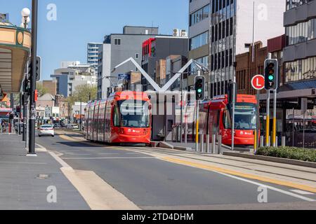 Paysage urbain de jour à Newcastle, Nouvelle-Galles du Sud, Australie, avec deux trains légers à l'arrêt. Ciel clair et journée ensoleillée, peu de gens en vue. Banque D'Images