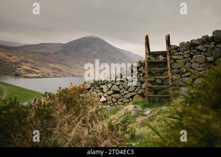 Un stile au-dessus du mur de Mourne sur les pentes de Moolieve Mountain avec le réservoir silencieux derrière, Mourne Mountains, County Down, Irlande du Nord. Banque D'Images