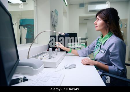 Un technologue en radiologie expérimenté utilise un système d'examen radiologique à distance Banque D'Images