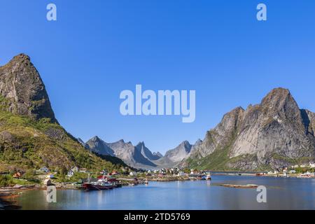 Vue panoramique grand-angle de Reine avec des maisons de rorbu rouge classiques nichées parmi les montagnes verdoyantes dans les îles Lofoten, Norvège, capturées sur un lieu paisible, Banque D'Images