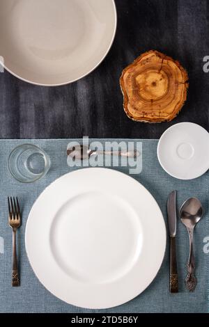 Assiettes, couverts, verre et nappe sur la vue de dessus de table noire. Pose à plat. Espace de copie. Banque D'Images