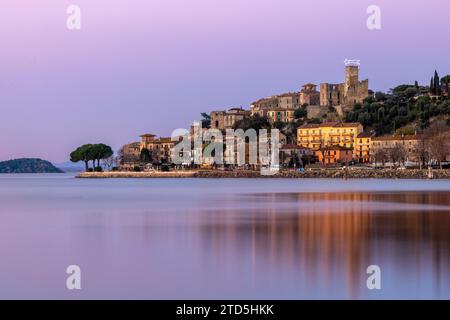 Village perché de Passignano reflété dans le lac Trasimeno, Ombrie, Italie Banque D'Images