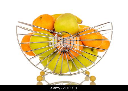 Plusieurs pommes vertes, mandarines et bananes dans un panier, macro, isolé sur fond blanc. Banque D'Images