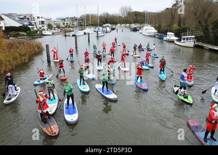 Groupe de paddle boarders habillés en Père Noël et Elfes. Événement de Noël organisé par le BH activité Junkieson la rivière Stour à Christchurch Dorset Royaume-Uni Banque D'Images