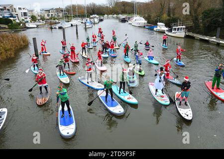 Groupe de paddle boarders habillés en Père Noël et Elfes. Événement de Noël organisé par les BH Activity Junkies sur la rivière Stour à Christchurch Dorset Royaume-Uni Banque D'Images