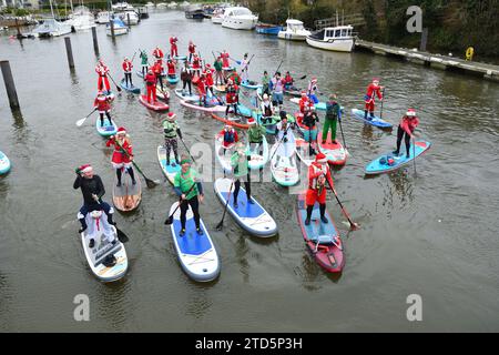 Groupe de paddle boarders habillés en Père Noël et Elfes. Événement de Noël organisé par les BH Activity Junkies sur la rivière Stour à Christchurch Dorset Royaume-Uni Banque D'Images