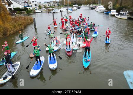 Groupe de paddle boarders habillés en Père Noël et Elfes. Événement de Noël organisé par les BH Activity Junkies sur la rivière Stour à Christchurch Dorset Royaume-Uni Banque D'Images