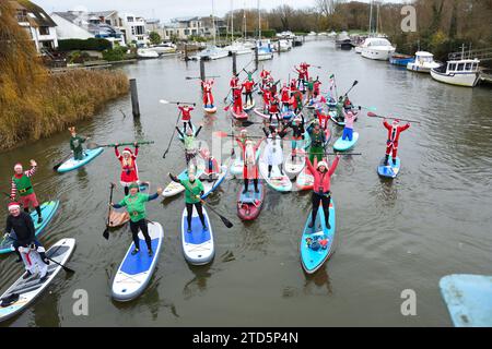 Groupe de paddle boarders habillés en Père Noël et Elfes. Événement de Noël organisé par les BH Activity Junkies sur la rivière Stour à Christchurch Dorset Royaume-Uni Banque D'Images