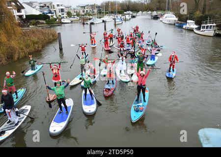 Groupe de paddle boarders habillés en Père Noël et Elfes. Événement de Noël organisé par les BH Activity Junkies sur la rivière Stour à Christchurch Dorset Royaume-Uni Banque D'Images