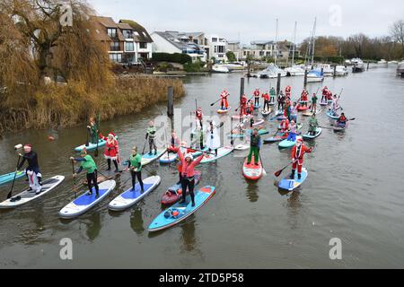 Groupe de paddle boarders habillés en Père Noël et Elfes. Événement de Noël organisé par les BH Activity Junkies sur la rivière Stour à Christchurch Dorset Royaume-Uni Banque D'Images