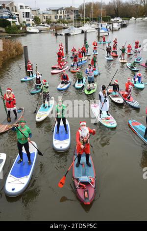 Groupe de paddle boarders habillés en Père Noël et Elfes. Événement de Noël organisé par les BH Activity Junkies sur la rivière Stour à Christchurch Dorset Royaume-Uni Banque D'Images