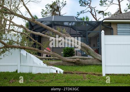 Dommages causés par un ouragan à la clôture blanche en PVC ruiné après que des débris d'arbres sont tombés dessus en Floride Banque D'Images