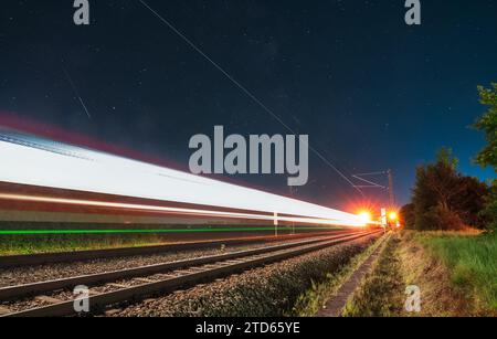 Sentiers légers d'un train à conduite rapide la nuit avec les étoiles de la voie lactée. Banque D'Images