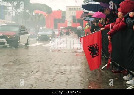 Tirana, Albanie - 28 novembre 2023 : sur l'avenue des Martyrs de la Nation, les citoyens regardent un défilé de voitures modifiées le jour de l'indépendance pluvieux, featuri Banque D'Images