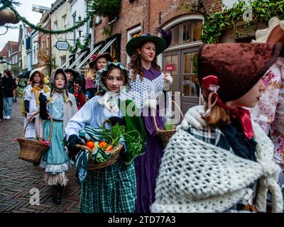 Deventer, pays-Bas . 16 décembre 2023. On voit des femmes marcher en ligne portant des vêtements victoriens. Chaque année, vers cette date, le monde du 19e siècle de l'écrivain anglais Charles Dickens revit dans la belle ville hollandaise de Deventer. Plus de 950 personnages des célèbres livres de Dickens remontent à la vie. Riches dames et messieurs avec des chapeaux de haut défilé dans les rues.le paysage du festival se compose de bâtiments historiques, arbres de Noël, et des milliers de petites lumières. Crédit : SOPA Images Limited/Alamy Live News Banque D'Images