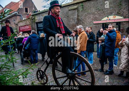 Deventer, pays-Bas . 16 décembre 2023. Un groupe d'hommes monte de vieux vélos. Chaque année, vers cette date, le monde du 19e siècle de l'écrivain anglais Charles Dickens revit dans la belle ville hollandaise de Deventer. Plus de 950 personnages des célèbres livres de Dickens remontent à la vie. Riches dames et messieurs avec des chapeaux de haut défilé dans les rues.le paysage du festival se compose de bâtiments historiques, arbres de Noël, et des milliers de petites lumières. Crédit : SOPA Images Limited/Alamy Live News Banque D'Images