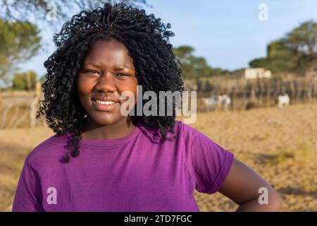 village jeune femme africaine, debout dans la cour dans une journée ensoleillée Banque D'Images