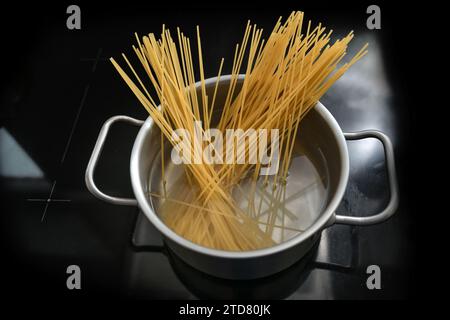 Les spaghettis sont bouillis dans une casserole d'eau sur une cuisinière noire, la cuisson des pâtes, l'espace de copie, le foyer sélectionné, la profondeur de champ étroite Banque D'Images