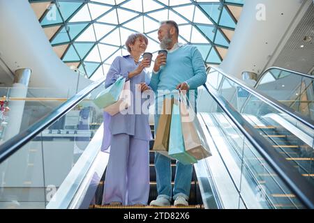 Couple de seniors descendant l'escalator du centre commercial Banque D'Images