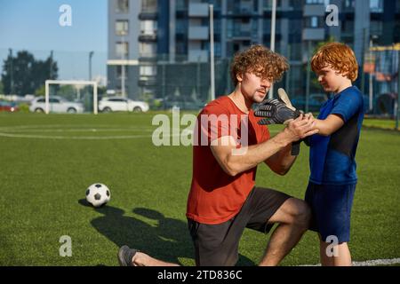 Père mettant des gants de gardien de but sur la main de son fils avant d'entraîner le football Banque D'Images