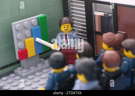 Tambov, Fédération de Russie - 16 décembre 2023 des figurines d'affaires Lego se réunissent dans une salle de réunion et discutent de graphiques montrant le RE Banque D'Images
