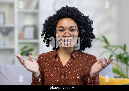 Portrait rapproché d'une jeune femme afro-américaine aux cheveux bouclés portant un casque, parlant et faisant des gestes devant la caméra. Banque D'Images