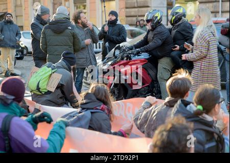 Rome, Italie. 16 décembre 2023. Des militants écologistes bloquent le passage d'un motocycliste lors de la manifestation du mouvement écologiste ''˜Ultima Generazione' à Rome. Plus de 100 militants écologistes de toute l'Italie ont participé à la manifestation de ''˜Ultima Generazione' (dernière génération) mouvement avec le slogan "nous sommes le pouvoir" à Rome pour rencontrer d'anciens et de nouveaux partisans de l'ambitieux projet de désobéissance civile afin de sensibiliser l'opinion publique et demander au gouvernement italien le "Fonds de réparation" : un fonds permanent et préventif de 20 milliards pour réparer les dommages causés Banque D'Images