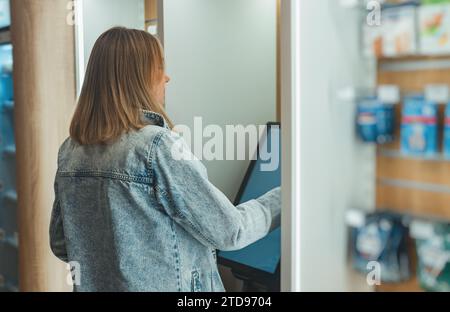 Femme utilise un terminal libre-service dans un magasin. Banque D'Images