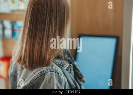 Femme utilise un terminal libre-service dans un magasin. Banque D'Images