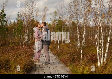 Les touristes avec des sacs à dos embrassent un chemin en bois dans un marais à Yelnya, Biélorussie. Banque D'Images