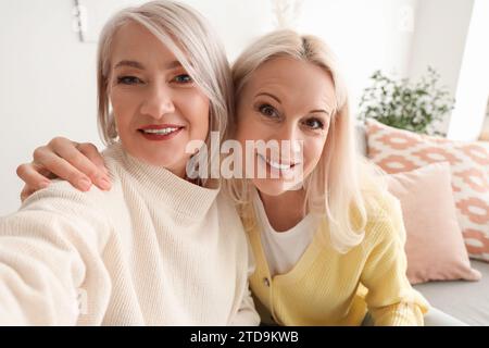 Amis féminins matures prenant selfie à la maison, closeup Banque D'Images