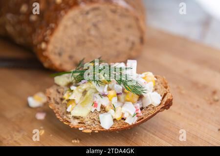 Une tranche de pain frais avec une salade de légumes et une branche d'aneth sur le dessus Banque D'Images