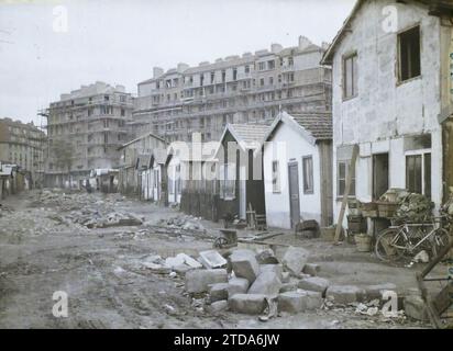 Paris (18e arrondissement), France transformation de la 'zone', sur le site des anciennes fortifications entre les portes de Clignancourt et Saint-Ouen, Transports, logement, Architecture, vie quotidienne, échafaudage, étaiement, transport de vélo, travaux, chariot, vannerie, habitation, objet domestique, fortifications, délabrement, conditions insalubres, caserne, gravats, France, Paris, caserne sur le terrain des fortifons et nouvelles constructions entre les portes de Clignancourt et St-Ouen, fortifications, petite ceinte, la zone, 20/09/1929 - 20/09/1929, Léon, Auguste, photographe, Autochrome, photo, Banque D'Images