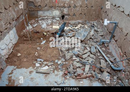 Rénovation complète de la salle de bains : carreaux de sol et de mur enlevés. Marteau de démolition électrique extra-robuste sur le sol. Banque D'Images