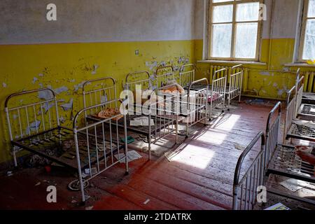 Cadres de lit en métal dans une pièce délabrée. Vieux lits d'enfants dans un jardin d'enfants abandonné. L'intérieur d'une pièce dans l'un des bâtiments du Chernob Banque D'Images