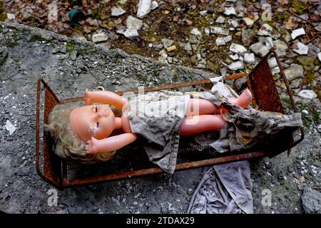 Une poupée jetée repose dans un lit rouillé au milieu des débris. Banque D'Images