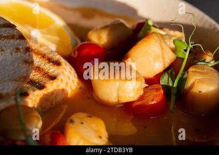 Coquilles Saint-Jacques portugaises frites dans une sauce au vin blanc avec citron, tomates et pain grillé. Fruits de mer, régime méditerranéen. Banque D'Images