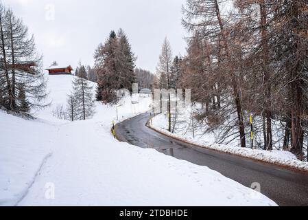 Route sinueuse vide dans un paysage de montagne enneigé sur une journée nuageuse d'hiver Banque D'Images