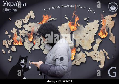 Kiev, Ukraine. 16 décembre 2023. Un homme marche près d'une maquette d'un timbre-poste avec l'inscription "l'Empire du mal doit tomber" et brûle les terres russes dans le centre de Kiev. (Photo Oleksii Chumachenko/SOPA Images/Sipa USA) crédit : SIPA USA/Alamy Live News Banque D'Images