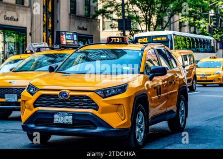New York, USA ; 31 mai 2023 : le taxi jaune typique de la Big Apple, descend la Cinquième Avenue au milieu de Manhattan, sous une journée ensoleillée. Banque D'Images
