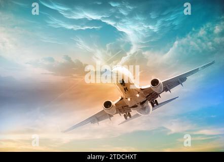 Un avion à réaction commercial vole au-dessus de nuages spectaculaires à la lumière d'un magnifique coucher de soleil. Concept de voyage. Nuages de couleur crème .le concept de voyage Banque D'Images