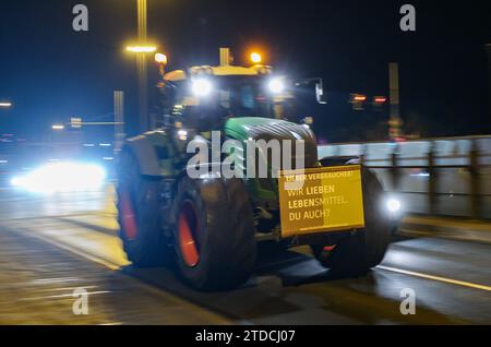 Leipzig, Allemagne. 18 décembre 2023. L'un des nombreux agriculteurs conduit dans la circulation des heures de pointe tôt le matin avec son tracteur et une affiche de protestation. Les agriculteurs veulent se mobiliser lundi à Berlin pour protester contre la suppression prévue des allégements fiscaux par la coalition des feux de circulation. Sous le slogan "trop c'est trop", un rassemblement est prévu à la porte de Brandebourg dans la matinée. Crédit : Jan Woitas/dpa/Alamy Live News Banque D'Images